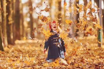Throwing leaves into the air. Cute positive little girl have fun in the autumn park