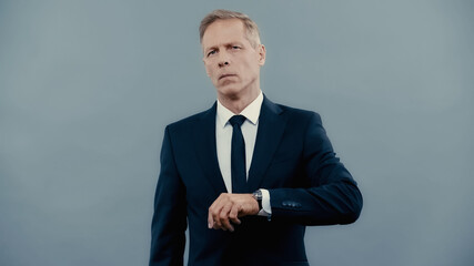 Middle aged businessman in suit looking at camera isolated on grey.
