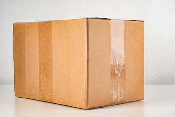 Cardboard box. Cardboard box without inscription. Box with scotch tape on light background. Concept packaging for shipping and transportation. Cardbox for transportation close-up.
