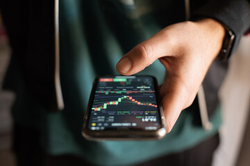 Investor thinking and analyzing graph stock market trading with stock chart data planning, financial and investment concept on smartphone. Front view