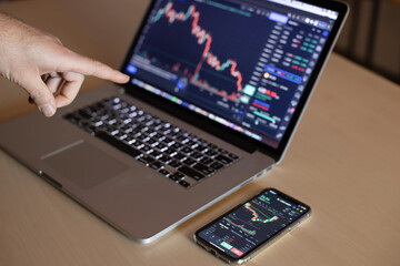 Man working with laptop computer and smartphone, thinking and analyzing graph stock market trading with stock chart data planning, financial and investment concept