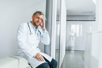 Naklejka na ściany i meble Feeling bad and tired. Professional medic in white coat is in the clinic