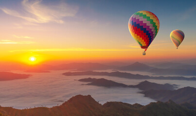 Fototapeta na wymiar Colorful hot air balloons flying over mountain misty morning sunrise