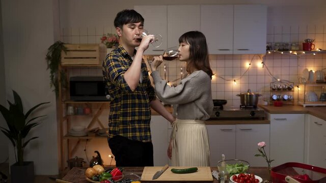 korean young couple flirting and enjoying champagne while celebrating valentine’s day at night in the kitchen at home