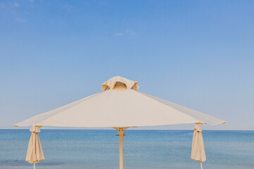 Beautiful view of white sand beach with sun umbrella and sunbed. Greece.