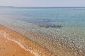 Beautiful view of white sand beach and turquoise waves. Turquoise sea water and blue sky. Greece.