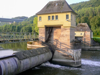 Water dam and hydro power plant building. Concrete bridge in the background. Industrial and...