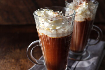 Coffee with Irish whiskey and whipped cream in glass on rustic wooden surface