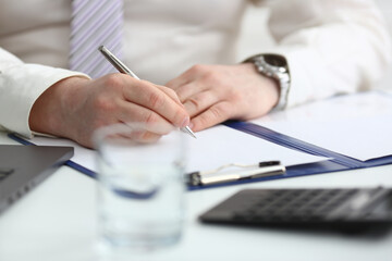 Man hand holds pen and fills out schedule of working day
