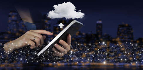 Hand touch white tablet with digital hologram cloud, download, data sign on city dark blurred background. Cloud computing technology internet concept background.