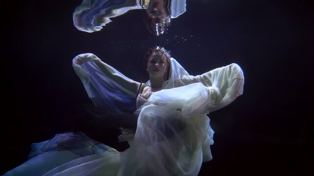 mysterious female figure underwater, slow motion shot with enigmatic beautiful woman