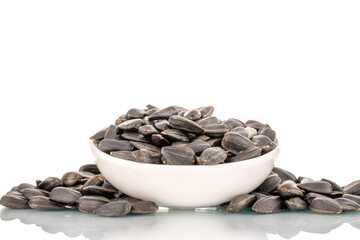 Many fragrant sunflower seeds with a white ceramic saucer, close-up, isolated on white.