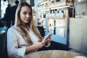 Young woman browsing smartphone at table of cafe