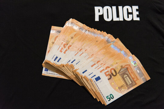 Une liasse de billets de 50 euros sur un t-shirt noir de police - format paysage