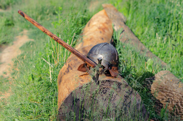 Fototapeta premium View of ancient Viking armor lying on a wooden log. Helmet and ax. Historical photo concept.
