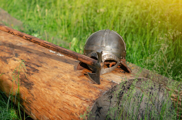 View of ancient Viking armor lying on a wooden log. Helmet and ax. Historical photo concept.