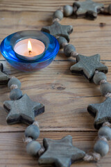 Top view of wooden stars with lit candle for meditation, on wooden table, in vertical, with copy space