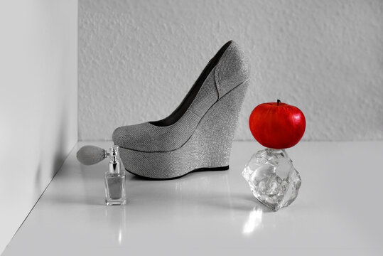 red apple on a glass piece, silver spray bottle on light background, womens high-heeled shoe, concept photography in high key style, vitamin fruit, gifts of nature and fashion