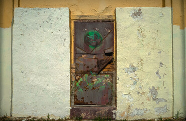 A rusty metal door in a concrete building.An old boarded-up door in the wall.