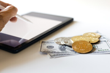 Focus on golden bitcoin with dollar and blurred human hand holding stylus pen pointing on tablet...