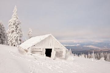 winter landscape with an abandoned, frozen, wooden hut