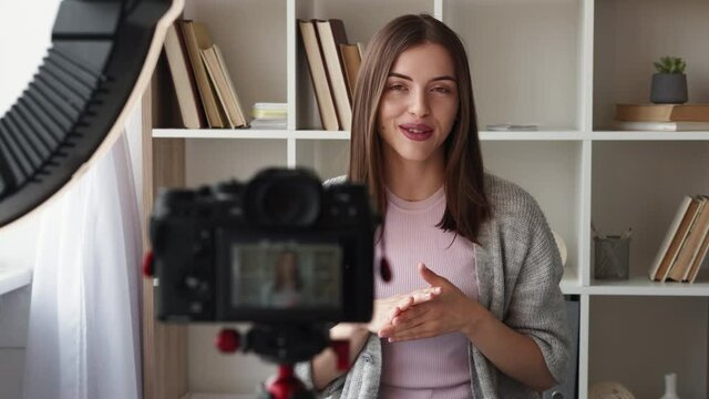 Video record. Influencer woman. Self presentation. Happy lady shooting on photo camera for personal blog sitting in light room interior.
