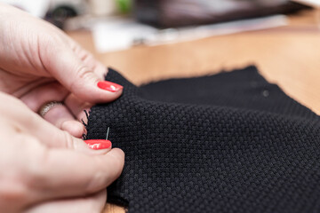 The dressmaker will open the fabric for the future costume for further work. Fashion designer tailor in the workshop of the studio, developing a new collection of clothes. 