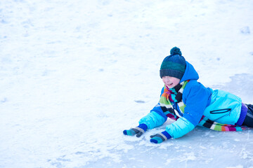 Fototapeta na wymiar the boy rolled down the ice slide and lies on his stomach in the snow in winter 