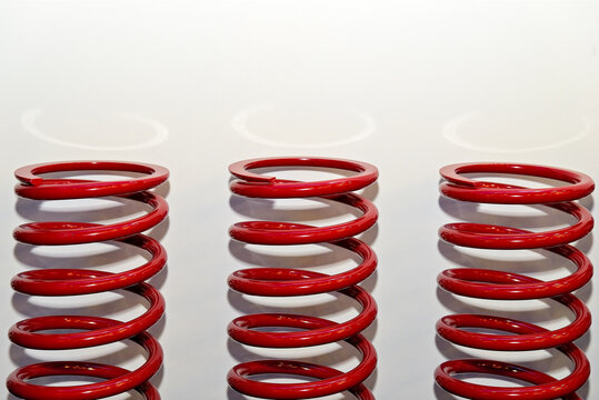 Three new spiral metal red springs on white background, helical car spring