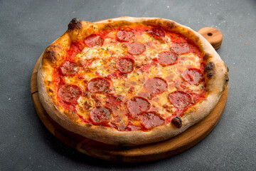 Pepperoni pizza on wooden board on grey concrete table