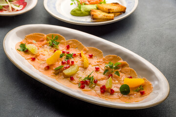 Salmon carpaccio on a plate on grey concrete table