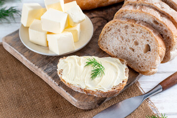 Craft toast bread and butter on a wooden cutting board. Simple breakfast on a wooden table. Close-up view