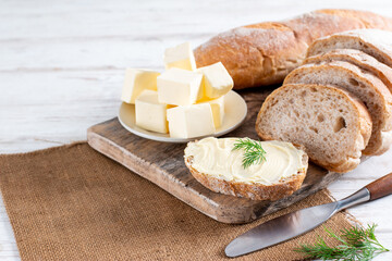 Butter and bread for breakfast, with dill on wooden table with copy space