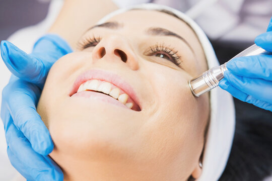Closeup photo of smiling woman receiving face cleaning procedure in cosmetology clinic, vacuum cleaning.