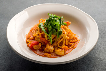 Pasta spaghetti with shrimps and tomato sauce on grey concrete table