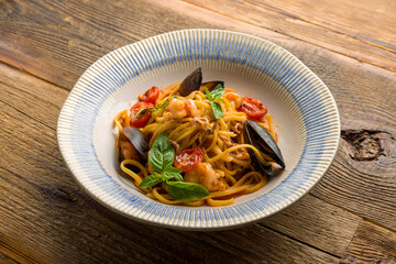 Pasta with seafood, shrimps, mussels and tomato sauce on old wooden table