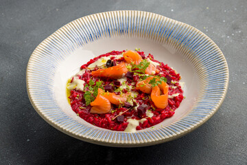 red risotto with salmon on grey concrete table