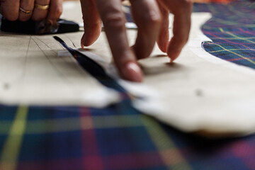 The dressmaker will open the fabric for the future costume for further work. Fashion designer tailor in the workshop of the studio, developing a new collection of clothes. 