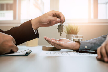 Realtor agent giving a key of apartment to new owner after signed lease agreement.