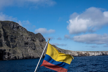 the flag of Ecuador on a ship against the backdrop of the landscape of the Galapagos Islands 