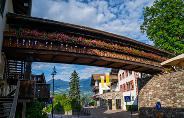 Obraz premium Traditional alpine houses with flowers on balcony. Colorful and picturesque village. Alpine village houses decorated with flowers street view.