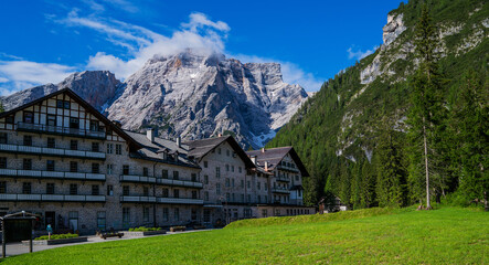 Fototapeta na wymiar Travel in northern Italy. Beautiful town surrounded by Dolomite mountains. Small village with view of mountains and modern resort building.