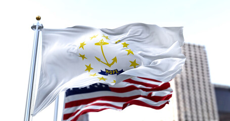 the flag of the US state of Rhode Island waving in the wind with the American flag blurred in the...