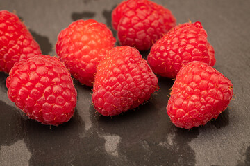 Close up f freshly washed raspberries on a slate cutting board