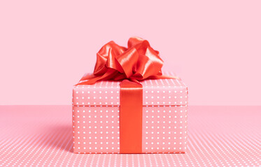 Pink gift box with a bow on a pink background. Close-up.