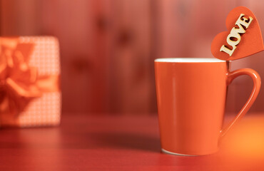 A red mug with a wooden heart with the inscription 