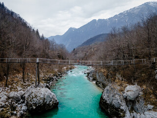 One person on bridge over Soca river during spring, julian alps in the background, Slovenia