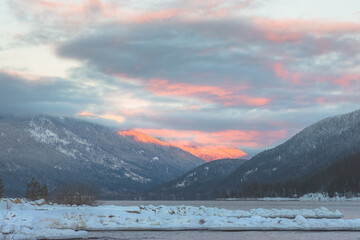 Sunrise or sunset on Kootenay lake with snow and mountains in Nelson, British Columbia, Canada during winter.