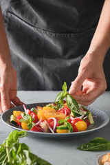 Woman cooking healthy italian Panzanella salad with fresh vegetables and crispy croutons.