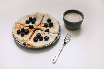 delicious breakfast with pancakes with blueberries on a white table and a coffee cup